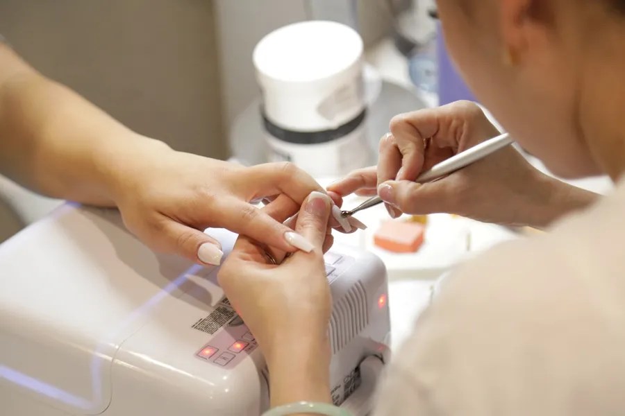 Bright, modern nail salon interior with pale wood manicure stations and large windows.